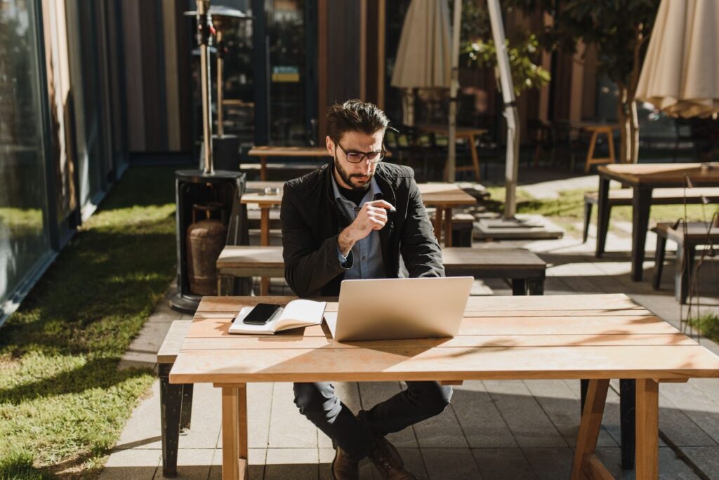 man in black jacket sitting on brown wooden picnic table