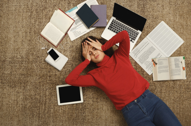 A tired person lying in a pile of studying materials