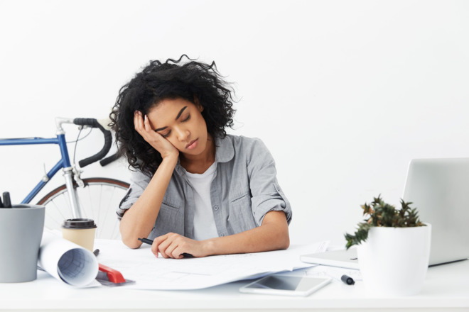 A tired person sleeping at a desk